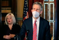 A photo of a man in a suit wearing a KN-95 mask at an official event.