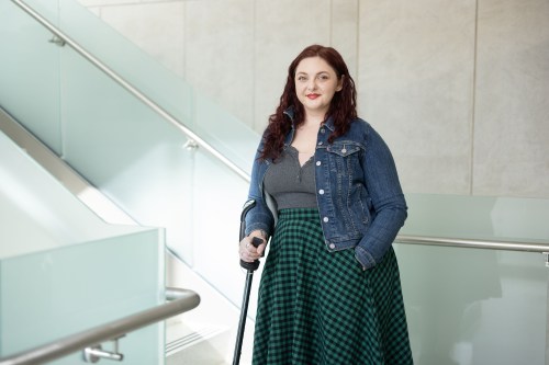 A portrait of a young woman leaning gently on a cane.