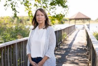 A photo of a woman standing outside on a dock by a gazebo.