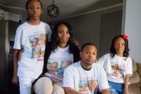 A family portrait taken indoors. From left to right, the adolescent son, mother, father, and young daughter. They are wearing matching T-shirts.