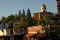 A photo of a historic downtown area of Auburn, California. Old buildings are seen alongside trees. A rotunda is seen on top of a tall building in the background.