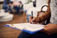 A photo of a woman in a medical office filling out a form.