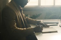 A photo of a psychologist writing in a notebook in a dark office.