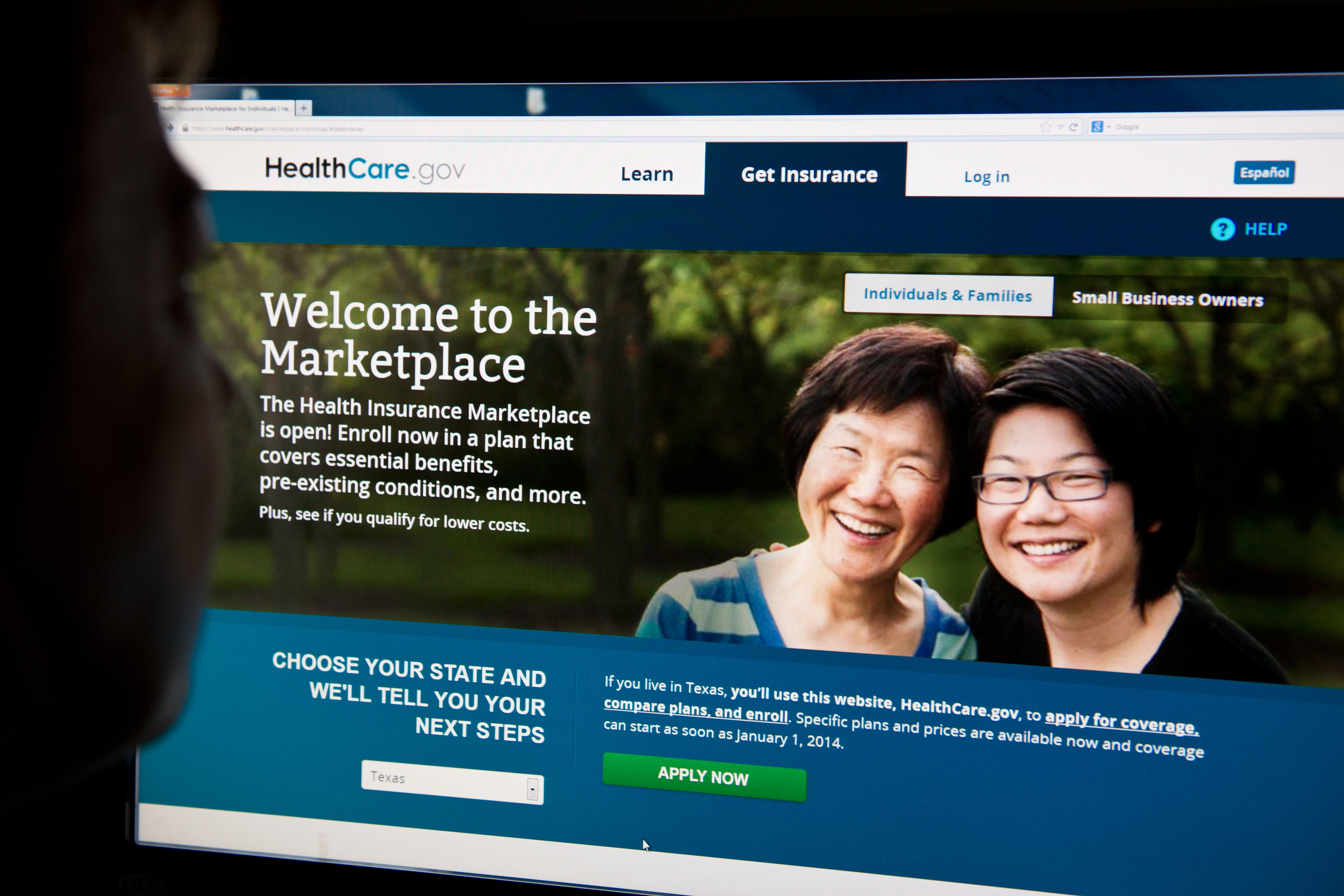 A photo of a computer screen showing the HealthCare.gov website. Text on the site reads, "The Health Insurance Marketplace is open! Enroll now in a plan that covers essential benefits, pre-existing conditions, and more."