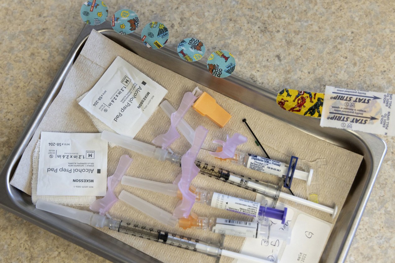 Alcohol pads, syringes, vaccines, and bandages lie on a tray at a pediatrician's office