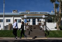 A photo of the exterior of a community hospital in rural Colorado. Two pedestrians walk across the sidewalk in front of it.