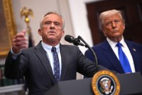 A photo of Robert F. Kennedy Jr. at a podium at the White House. President Trump stands to the right.