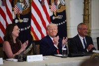 A photo of a White House event with three people sitting at the end of the table: Brooke Rollins, Donald Trump, and Robert F. Kennedy Jr.