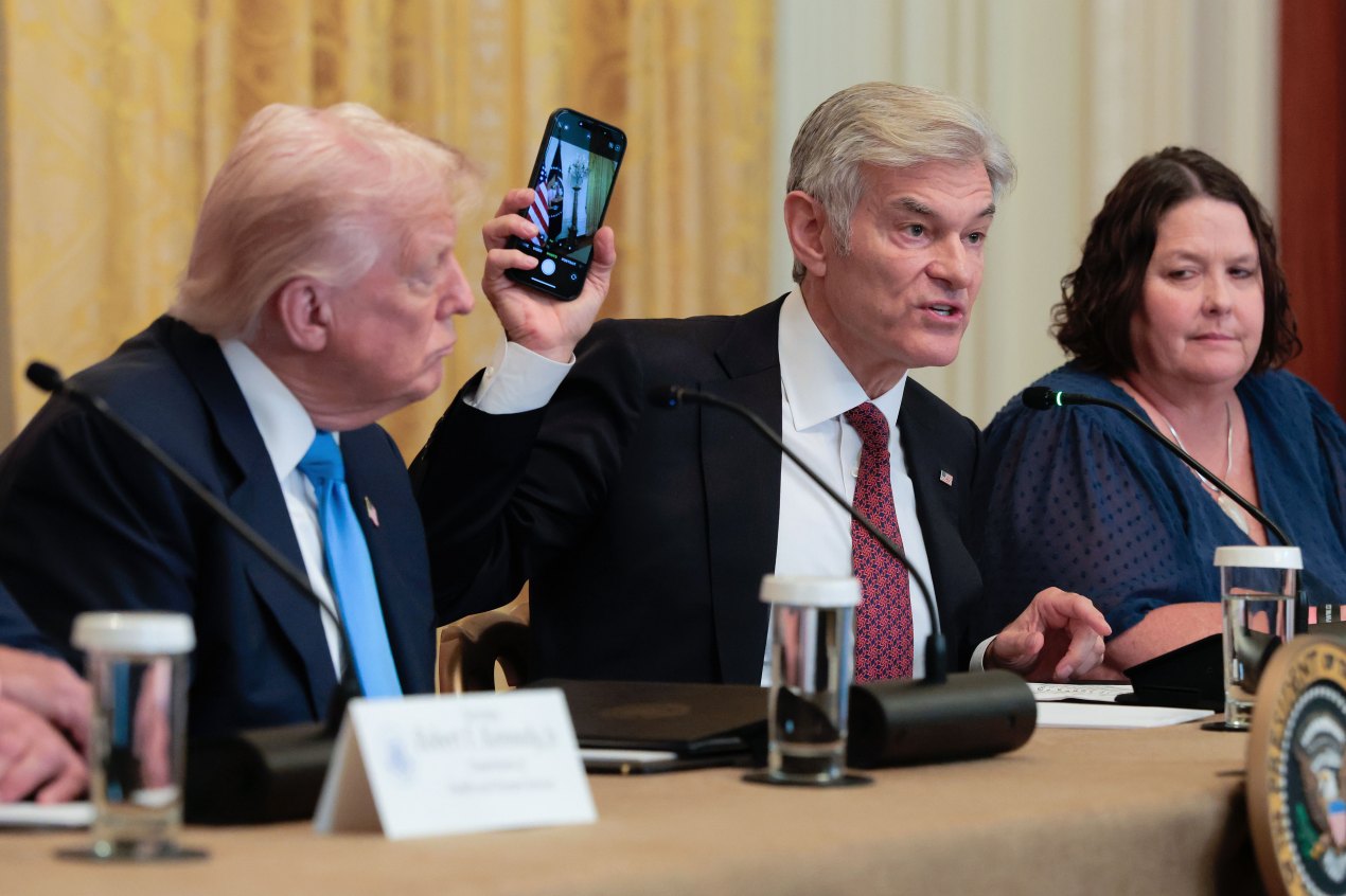 A photo of Mehmet Oz holding up a phone during a White House meeting about health care and technology.