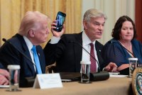 A photo of Mehmet Oz holding up a phone during a White House meeting about health care and technology.