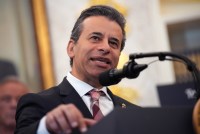 A close-up photograph of Marty Makary speaking into a microphone at a podium.