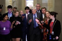 A photo of Sen. Cassidy walking as reporters flank him on both sides.