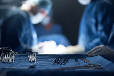 Surgery tools sit in the foreground as surgeons work in the background