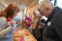 A photo of a woman leading a group of older adults in a game with hand bells.