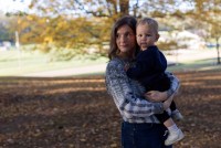 A photo of a woman holding her toddler outside.