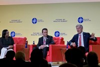 A photo of a panel on a stage. Mehmet Oz, Marty Makary, and Esther Krofah are seated, speaking to each other.