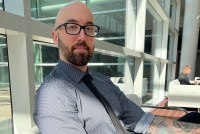 A photo of a man sitting indoors.