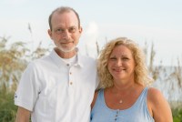 A photo of a husband and wife standing on the beach.