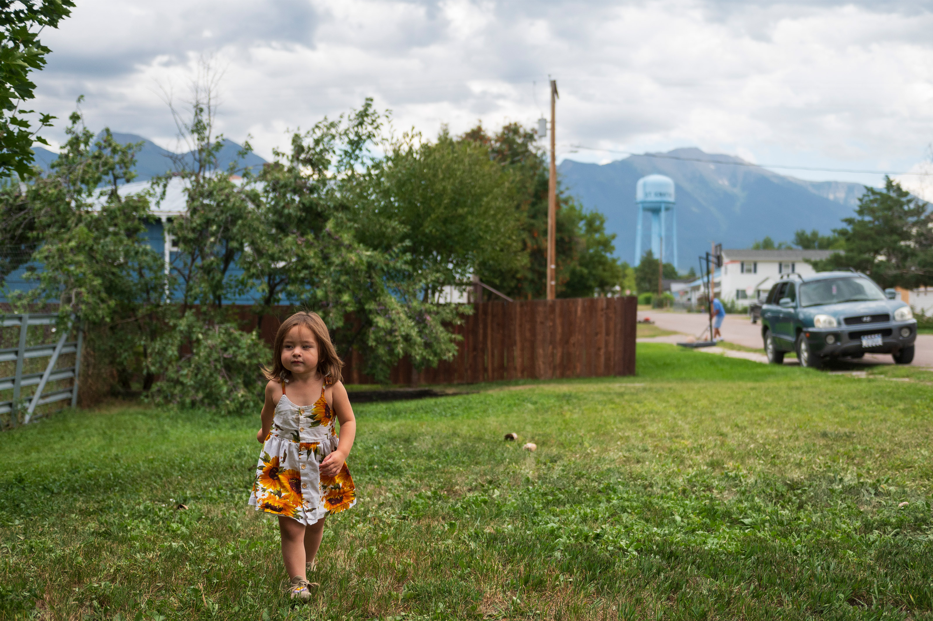A photo of young toddler walking in her front yard.